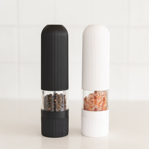 Black and white pepper grinders on a light background