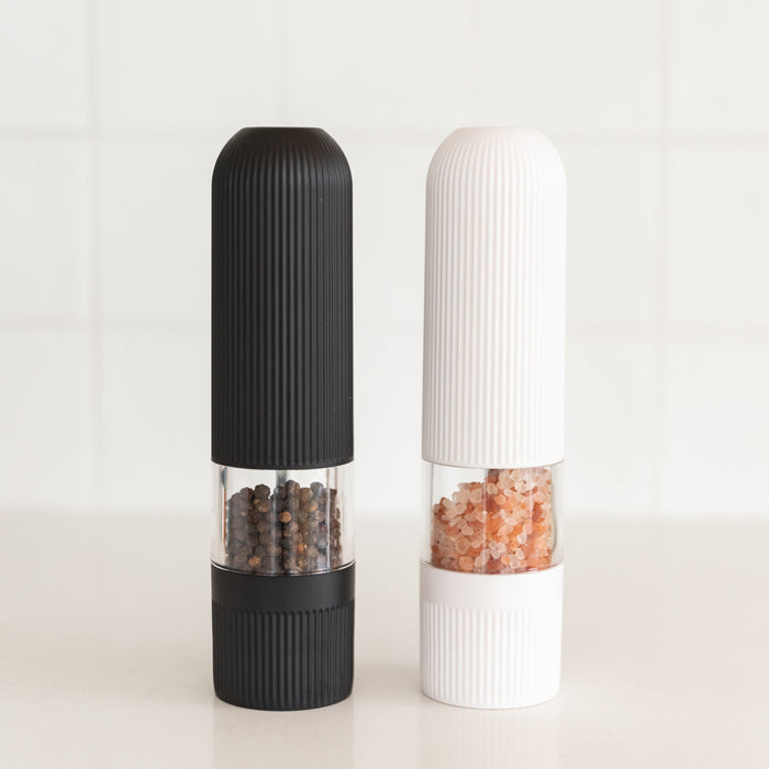 Black and white pepper grinders on a light background
